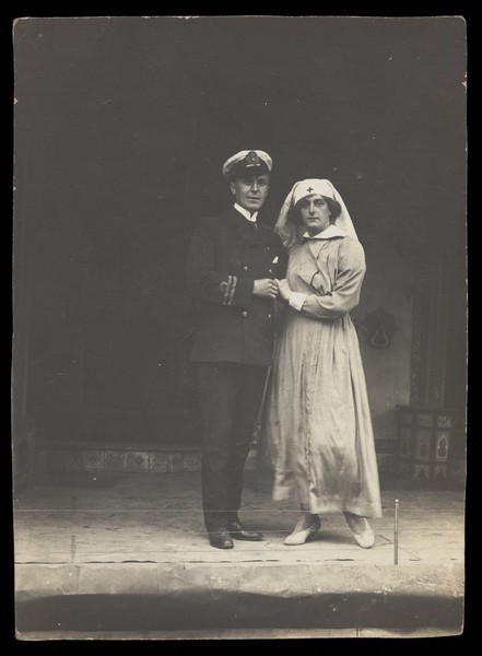 Download the full-sized image of A couple of sailors, one in drag, pose together on stage. Photographic postcard, 191-.
