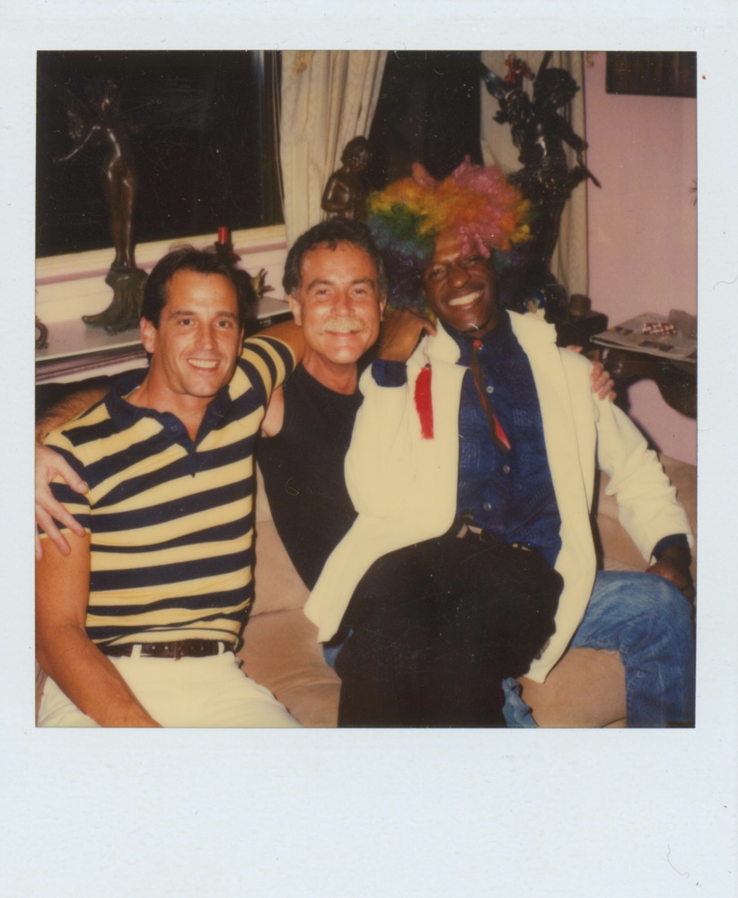 Download the full-sized image of A Photograph of Marsha P. Johnson Sitting on a Friend’s Lap With Rainbow Hair and a White Jacket
