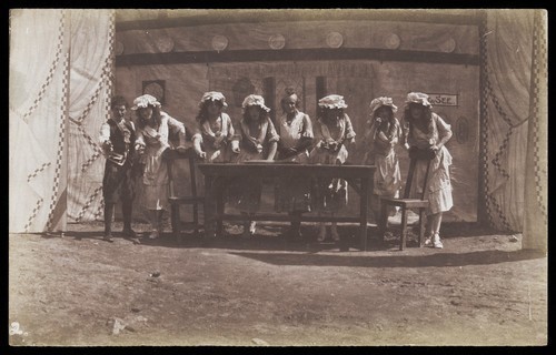 Download the full-sized image of British servicemen in drag acting out a cooking class. Photograph, 191-.