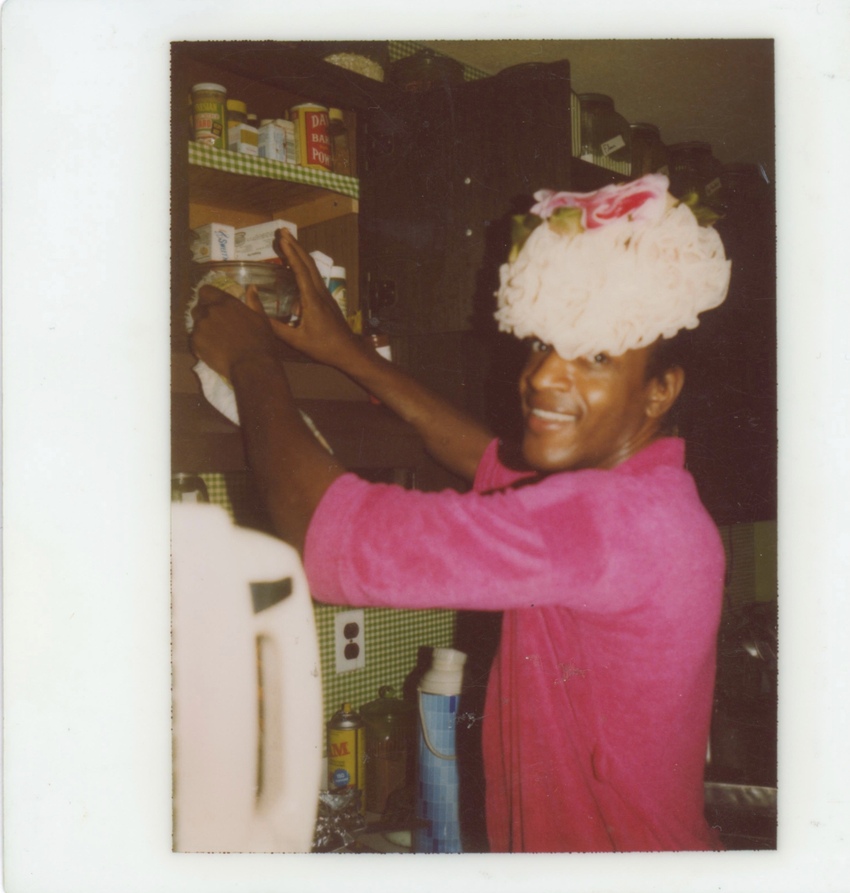 Download the full-sized image of A Photograph of Marsha P. Johnson Wearing a Pink Top and Reaching into a Cabinet