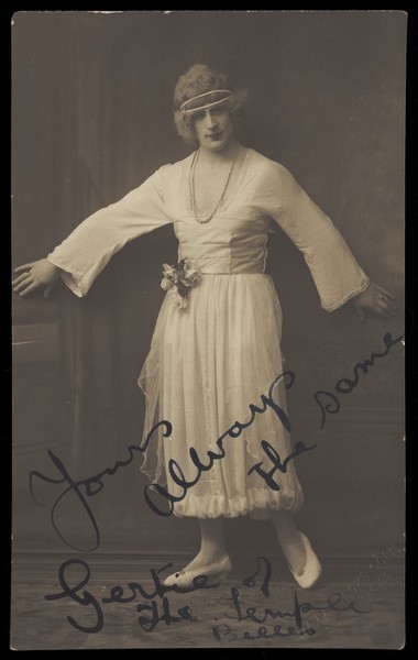 Download the full-sized image of An actor in drag, known as "Gertie", poses mid-movement in a white dress. Photographic postcard, 191-.