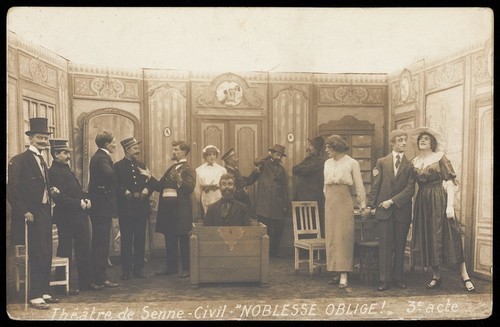 Download the full-sized image of Prisoners of war, some in drag, posing on stage during a crowded scene of "Noblesse oblige"; at Sennelager prisoner of war camp in Germany. Photographic postcard, 191-.