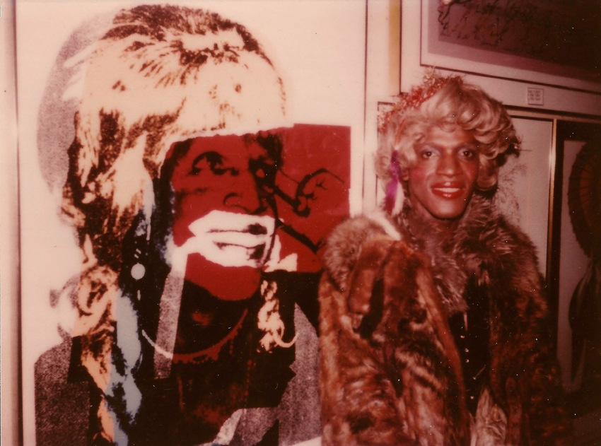 Download the full-sized image of A Photograph of Marsha P. Johnson Standing in Front of a 1975 Portrait of Her by Andy Warhol