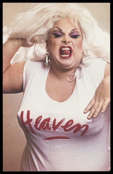 Download the full-sized image of "Divine" in character, wearing a "Heaven" t-shirt. Colour photographic postcard, 198-.