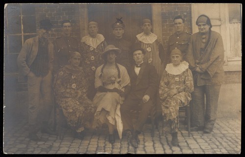 Download the full-sized image of British soldiers in France, one in drag, pose for a group portrait. Photographic postcard, 191-.