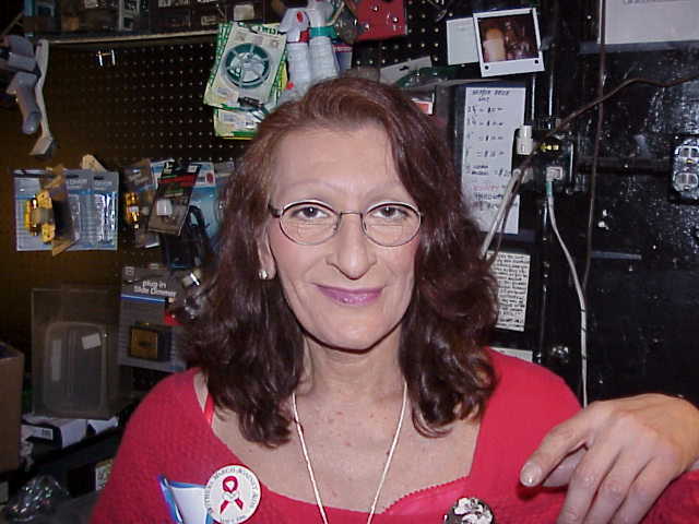 Download the full-sized image of A Photograph of Sylvia Rivera Smiling, Wearing a Red Shirt with a AIDS/HIV Ribbon Button