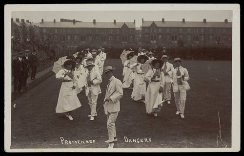 Download the full-sized image of Professional actors, some in drag, dance on a lawn as "Promenade dancers". Photographic postcard, 191-.