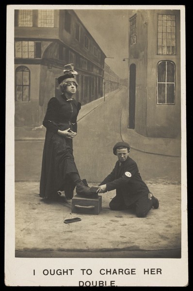 Download the full-sized image of A shoeshine boy cleans the boots of a man in drag. Photographic postcard, ca. 1905.